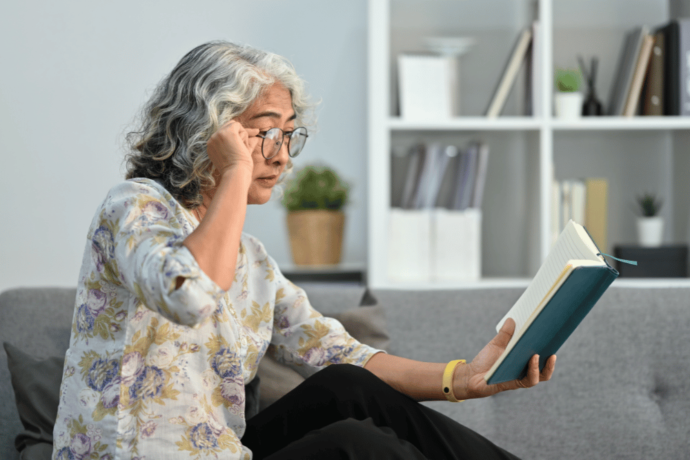 an older woman having trouble seeing a book in front of her